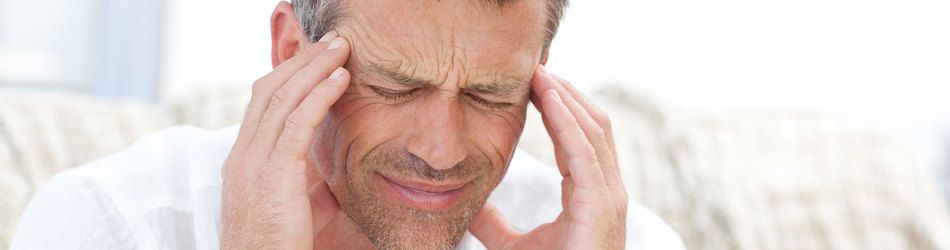 Man with TMJ grimacing and holding his temples